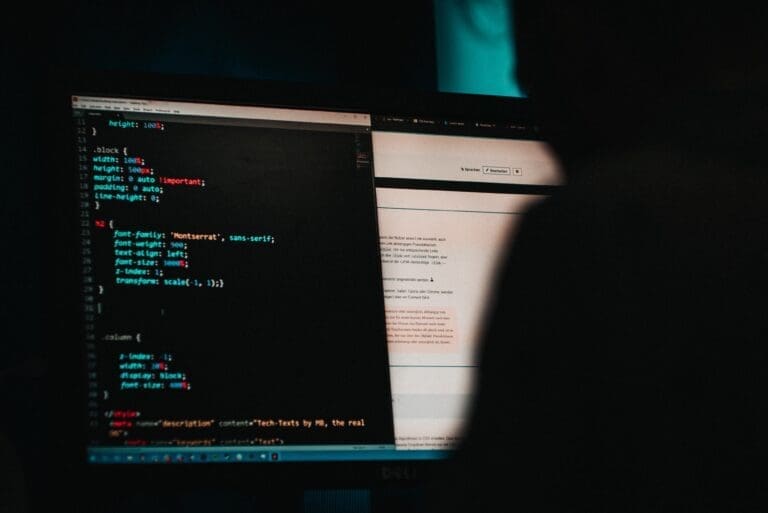 Photograph of dark room with computer screen with HTML code.
